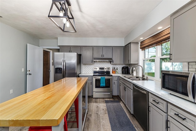 2056 Broken Arrow Trl N, Lakeland, FL 33813 - kitchen with stainless steel appliances, gray cabinets, dark wood-type flooring, under cabinet range hood, and decorative backsplash