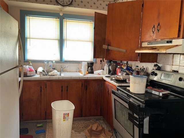 724 Ave D SW, Winter Haven, FL 33880 - kitchen with electric range, freestanding refrigerator, under cabinet range hood, tasteful backsplash, and tile counters