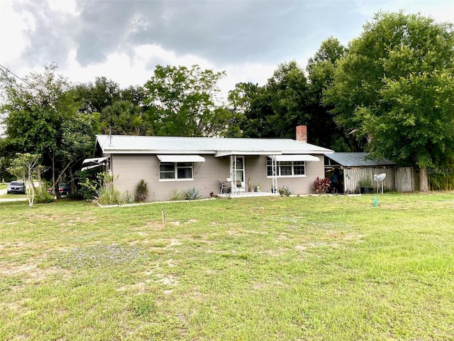 ranch-style home with a storage unit and a front lawn