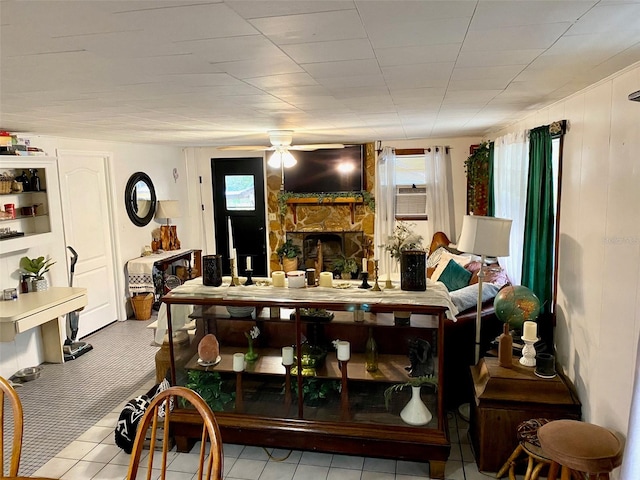 tiled dining room with ceiling fan and a fireplace