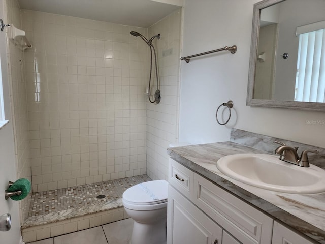 bathroom with vanity, tile flooring, toilet, and tiled shower