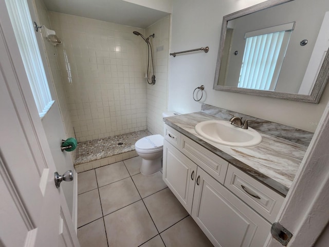 bathroom with a tile shower, tile flooring, large vanity, and toilet