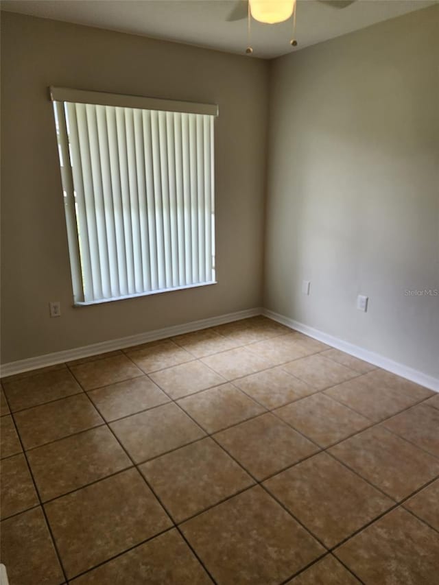 tiled empty room with a healthy amount of sunlight and ceiling fan