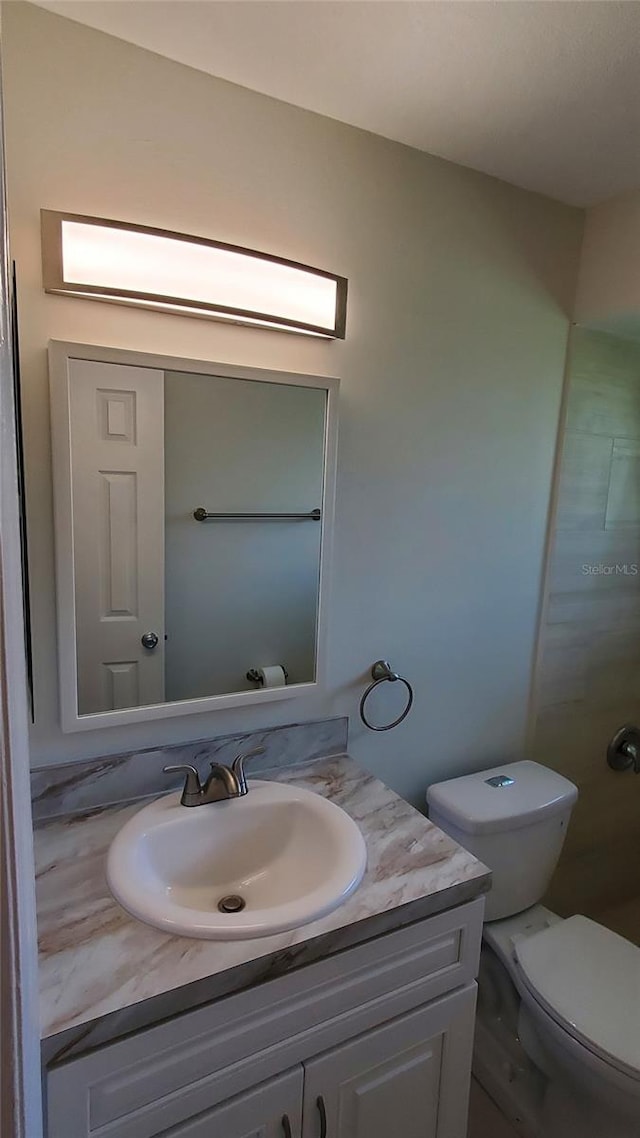 bathroom with toilet and vanity with extensive cabinet space