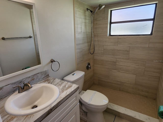 bathroom with toilet, a tile shower, and vanity