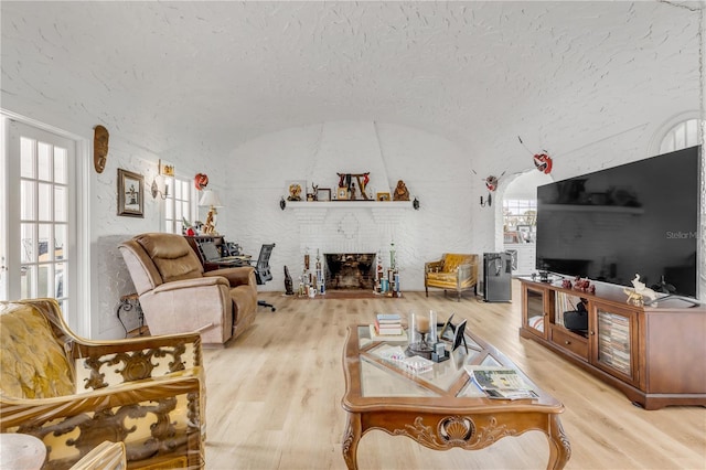 living room with plenty of natural light, light hardwood / wood-style flooring, a textured ceiling, and a fireplace