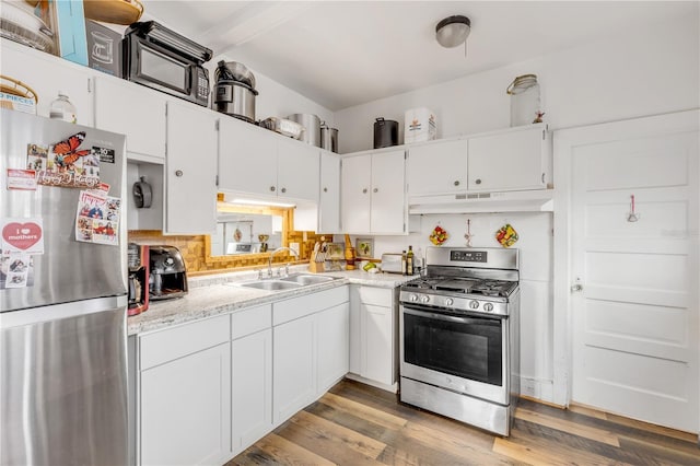 kitchen featuring hardwood / wood-style floors, white cabinets, appliances with stainless steel finishes, and sink