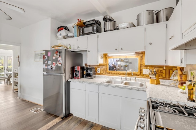 kitchen featuring white cabinets, backsplash, sink, and light wood-type flooring