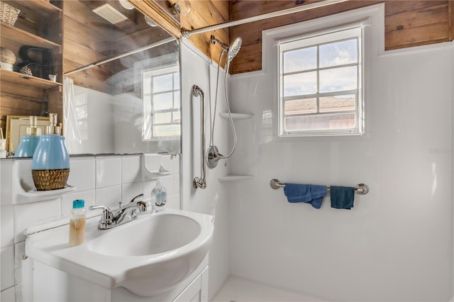 bathroom with backsplash, tile walls, oversized vanity, and a wealth of natural light