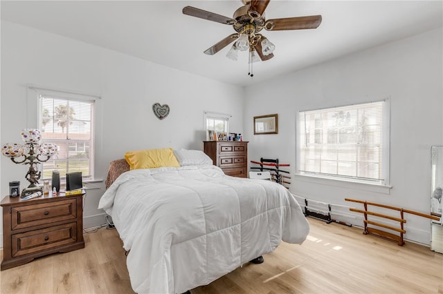 bedroom with light hardwood / wood-style floors, ceiling fan, and multiple windows