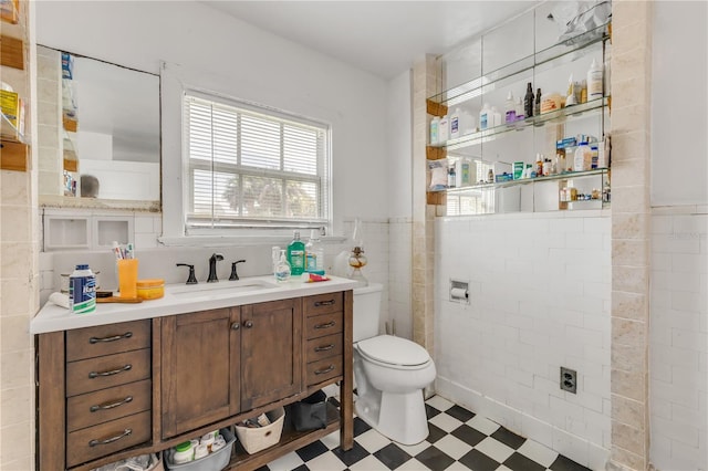 bathroom with vanity, tile flooring, toilet, and tile walls