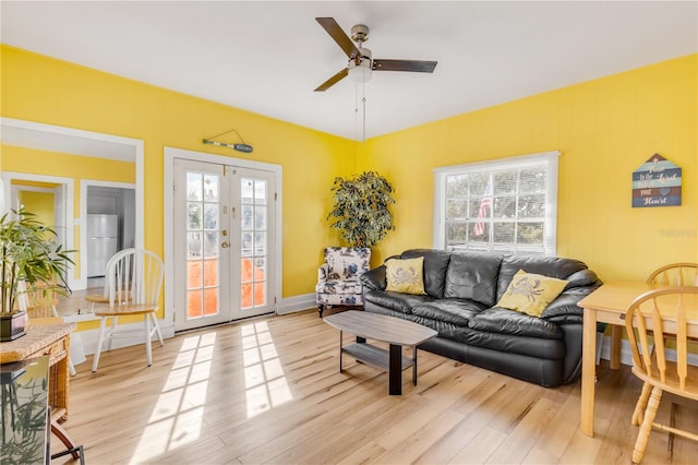 living room featuring french doors, plenty of natural light, ceiling fan, and light wood-type flooring