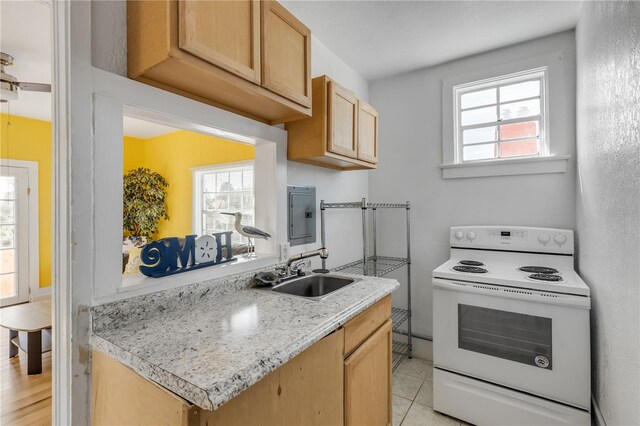 kitchen featuring sink, white range with electric cooktop, a healthy amount of sunlight, and light tile flooring