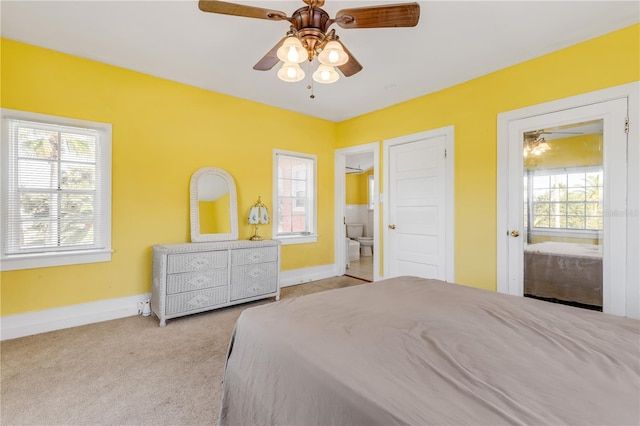 carpeted bedroom featuring connected bathroom, multiple windows, and ceiling fan