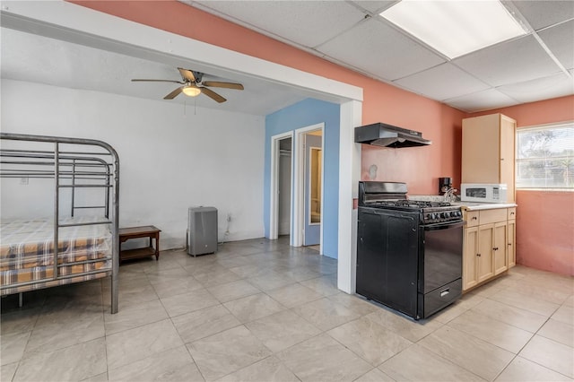 kitchen featuring black range with gas cooktop, ceiling fan, light tile floors, a paneled ceiling, and wall chimney exhaust hood