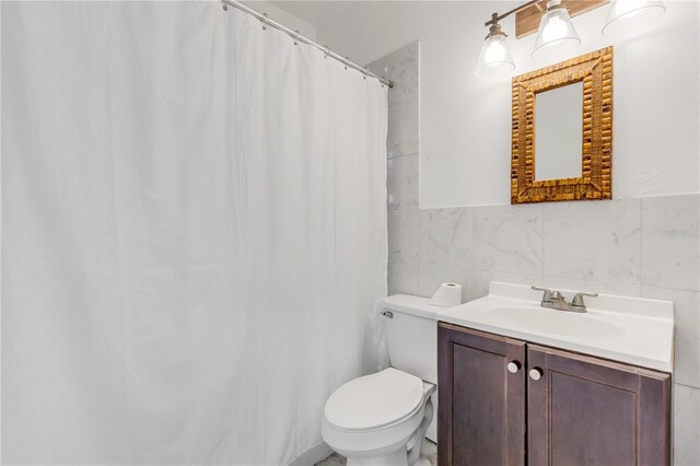 bathroom featuring tasteful backsplash, oversized vanity, toilet, and tile walls