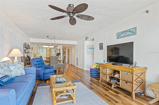 living room with ceiling fan, a textured ceiling, and dark hardwood / wood-style flooring