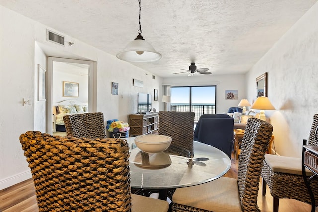dining room featuring light hardwood / wood-style floors, ceiling fan, and a textured ceiling