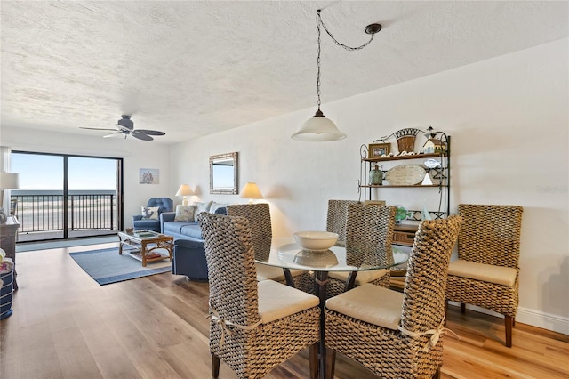 dining space with light hardwood / wood-style flooring, ceiling fan, and a textured ceiling