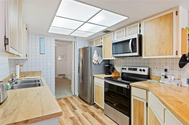 kitchen featuring light brown cabinets, appliances with stainless steel finishes, backsplash, light wood-type flooring, and sink