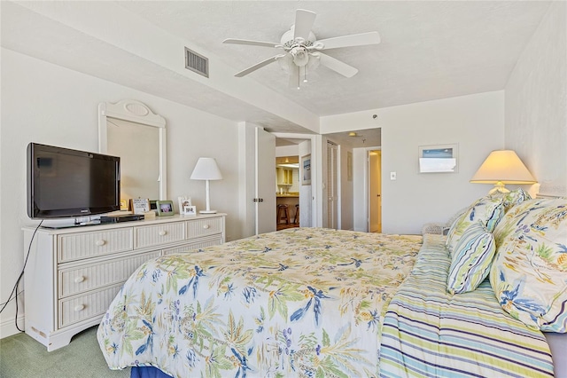 carpeted bedroom with ensuite bath and ceiling fan