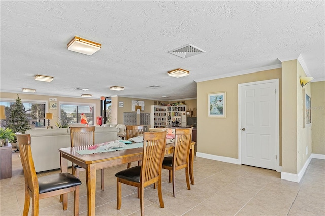 dining room with light tile floors, a textured ceiling, and ornamental molding