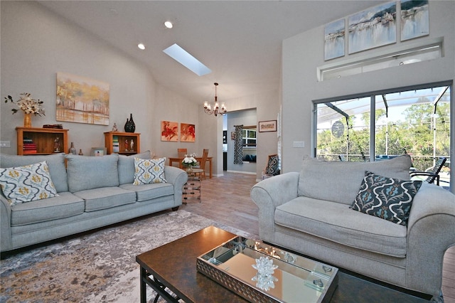 living room with hardwood / wood-style floors, a skylight, a chandelier, and high vaulted ceiling