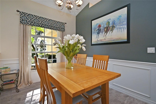 dining space with vaulted ceiling, wood-type flooring, a healthy amount of sunlight, and a notable chandelier