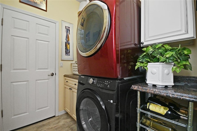 clothes washing area featuring cabinets, stacked washing maching and dryer, and light hardwood / wood-style flooring