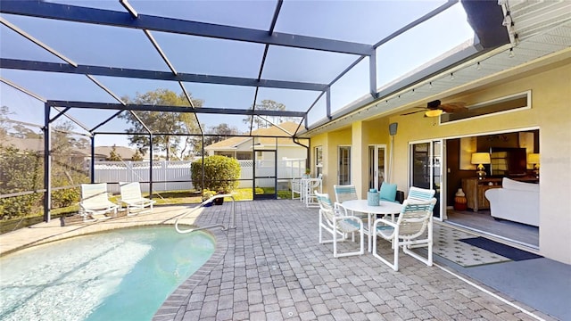 view of swimming pool featuring a patio, ceiling fan, and glass enclosure