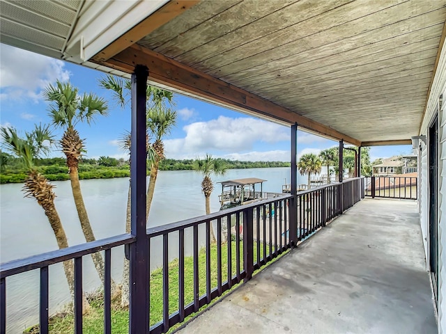 view of patio / terrace featuring a water view, a boat dock, and a balcony