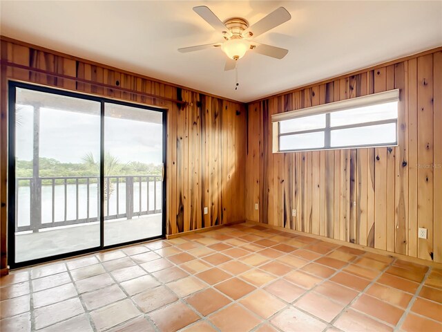 empty room with light tile floors, wooden walls, and ceiling fan