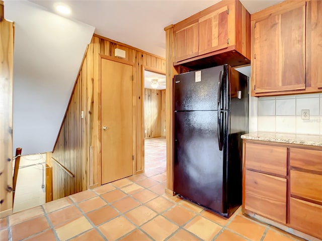 kitchen with light tile flooring, tasteful backsplash, black refrigerator, and tile counters