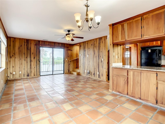 interior space with wood walls and ceiling fan with notable chandelier