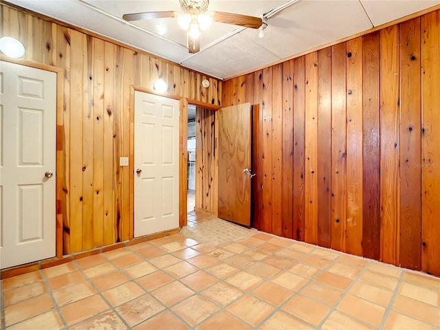 tiled spare room featuring wood walls and ceiling fan