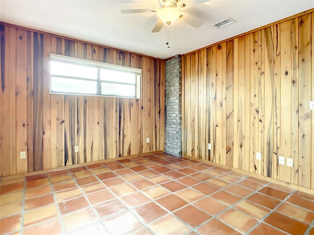 empty room with brick wall, wooden walls, tile floors, and ceiling fan