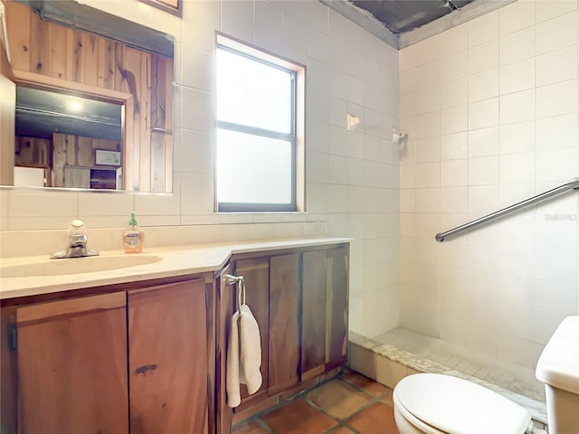 bathroom with vanity, tile walls, tile floors, tiled shower, and toilet