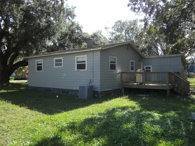 rear view of property featuring a lawn, a deck, and central air condition unit