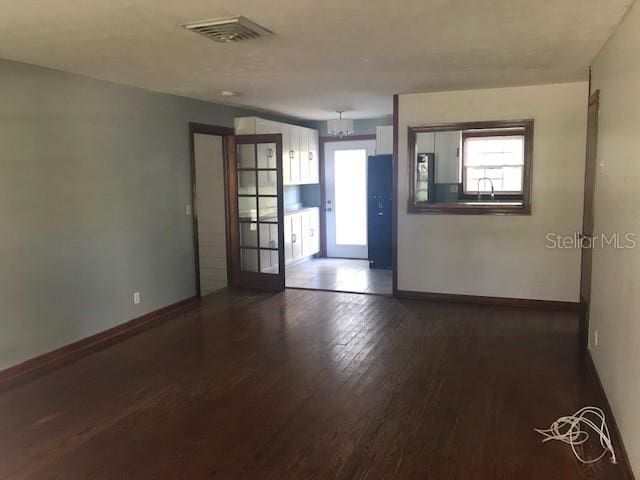 spare room with a healthy amount of sunlight and dark wood-type flooring