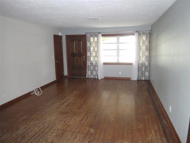 unfurnished room featuring a textured ceiling and dark wood-type flooring