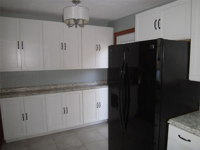 kitchen featuring a chandelier, light tile floors, white cabinets, and black fridge