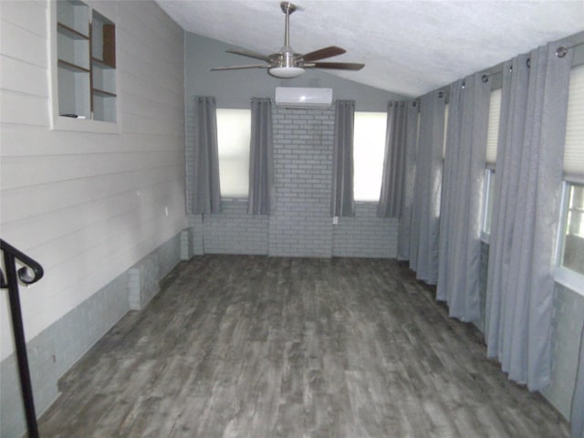 empty room with ceiling fan, dark wood-type flooring, brick wall, a textured ceiling, and vaulted ceiling