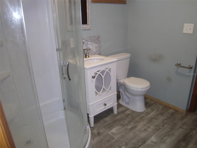 bathroom with an enclosed shower, toilet, wood-type flooring, and vanity