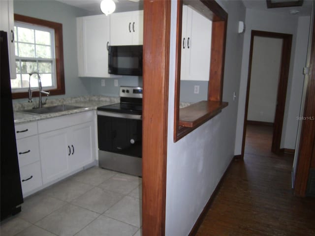 kitchen with sink, light wood-type flooring, white cabinets, light stone counters, and stainless steel electric stove