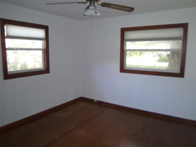 empty room with plenty of natural light, dark wood-type flooring, and ceiling fan