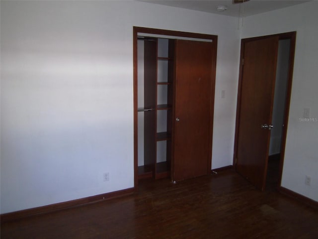 unfurnished bedroom with dark hardwood / wood-style flooring and a closet