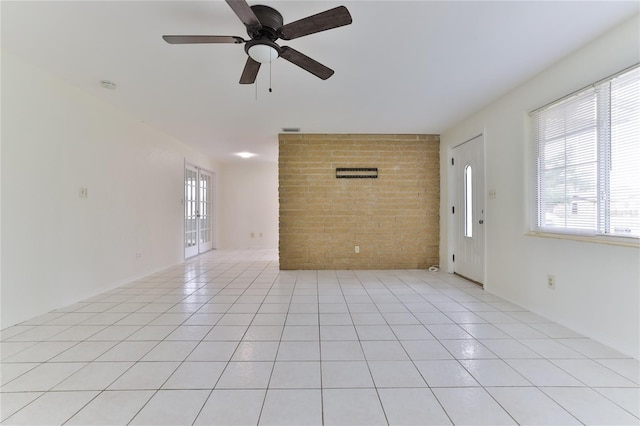 unfurnished room with brick wall, light tile flooring, and ceiling fan