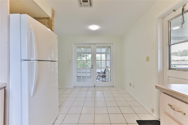 kitchen featuring light brown cabinets, light tile floors, white refrigerator, and french doors