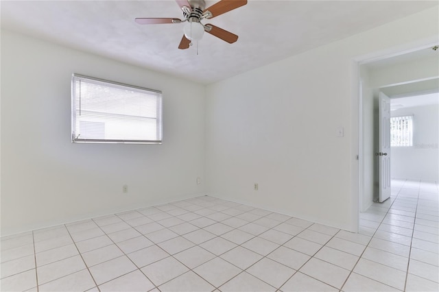 empty room with light tile flooring, a healthy amount of sunlight, and ceiling fan