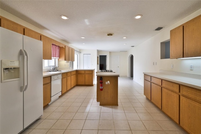 kitchen featuring light tile floors, a center island, white appliances, and sink